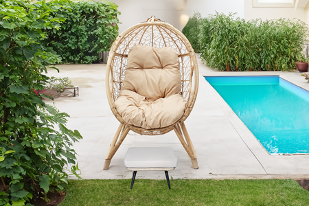 Conjunto de exterior con sillón con patas efecto ratán y reposapiés con cojín beige rectangular concept u